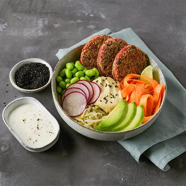 Bowl com hambúrgueres de beterraba, húmus e vegetais coloridos